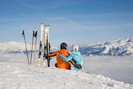 Een stel geniet tijdens het skiën van het uitzicht op besneeuwde bergen