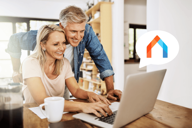 A couple looks at a laptop with a speech bubble containing the atraveo by e-domizil logo.