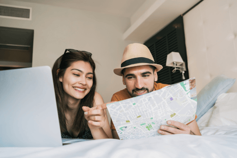 Una coppia pianifica una vacanza con l'aiuto di un computer portatile e di una mappa
