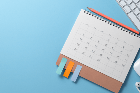 Ein aufgeschlagener Kalender und ein Stift liegen auf einem Schreibtisch.