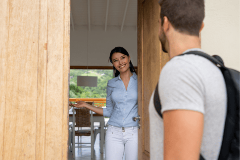 Eine Gastgeberin begrüßt einen Gast an der Tür ihrer Ferienunterkunft
